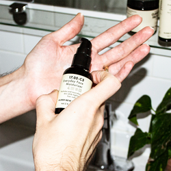 Male hand over a bathroom sink about to use Alder New York's Everyday Moisturizer.