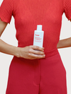 Woman on Red holding Scarlet Daily Cleanser with Organic Jojoba & Colloidal Silver